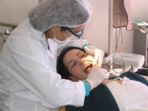 Woman laying in dental chair while dentist cleans her teeth