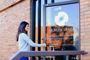 Young woman opening the front door to Akron Smile